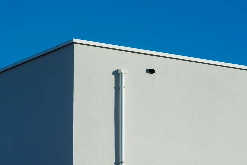 Bâtiment à toit plat avec acrotère et descente d'eau pluviale en façade