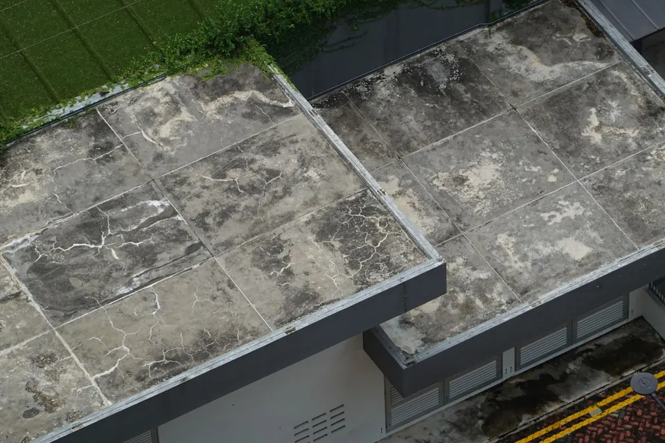 Toit-terrasse ancien couvert de dalles tachées, rive métallique